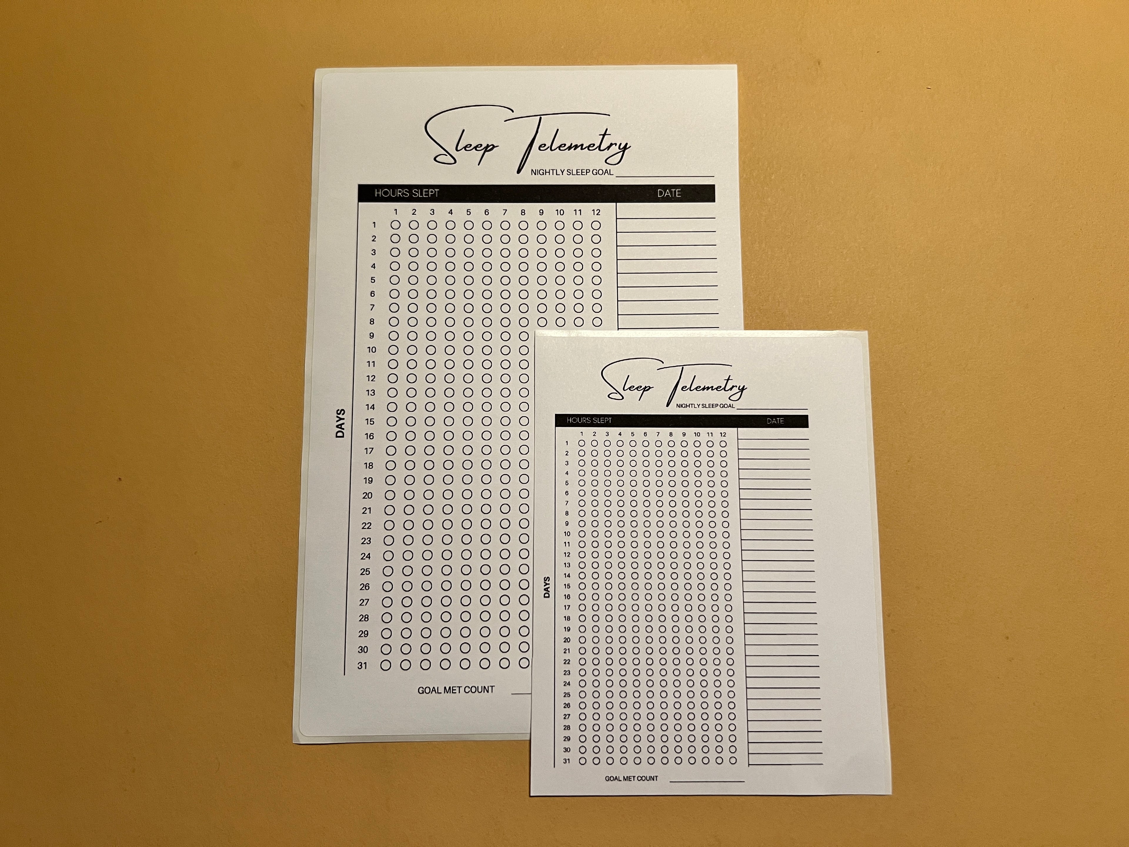 Two sheets of paper with sleep telemetry tracking forms on a brown background